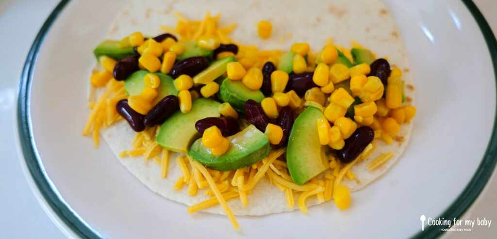 Avocado, red kidney beans, corn, and cheddar in a tortilla for baby quesadillas