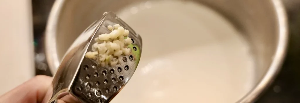 Pressing garlic to season the gratin